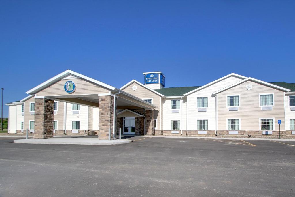 un grand bâtiment blanc avec un parking en face dans l'établissement Cobblestone Inn & Suites - Avoca, à Avoca