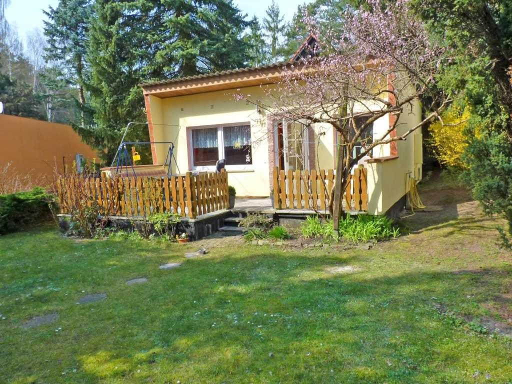 una piccola casa gialla con una recinzione in un cortile di Ferienhaus "Fleesensee" Objekt ID 11956-6 a Silz
