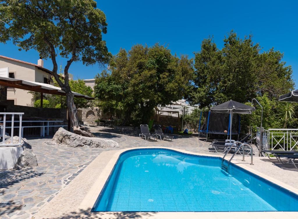 a swimming pool in a resort with chairs and an umbrella at Kefali Villa, eco tourism experience, By ThinkVilla in Atsipádhes