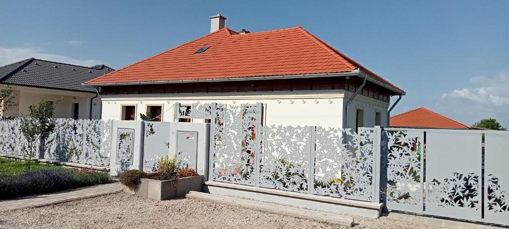 einen weißen Zaun vor einem Haus in der Unterkunft Bíbic Apartman C in Kápolnásnyék