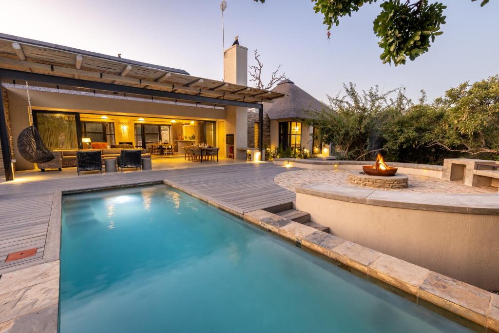 una piscina en un patio trasero con una hoguera en Kruger River Lodge, en Hoedspruit