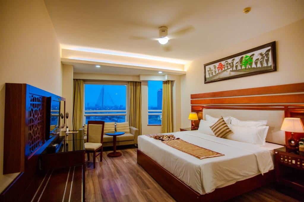 ダナンにあるMinh Toan Athena Hotelのベッド、デスク、窓が備わるホテルルームです。