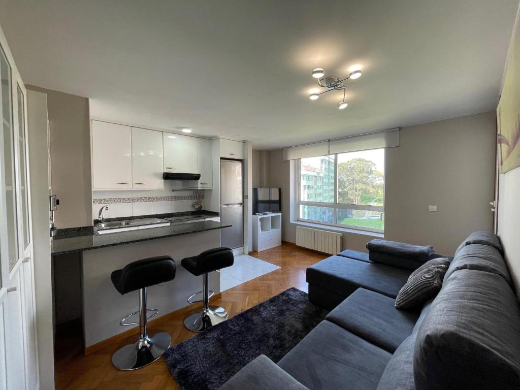 ein Wohnzimmer mit einem Sofa und einer Küche in der Unterkunft housingcoruña ROSALES in A Coruña