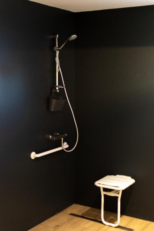 a shower in a black wall with a bench and a table at Vakantieverblijf De Backstage in Heuvelland