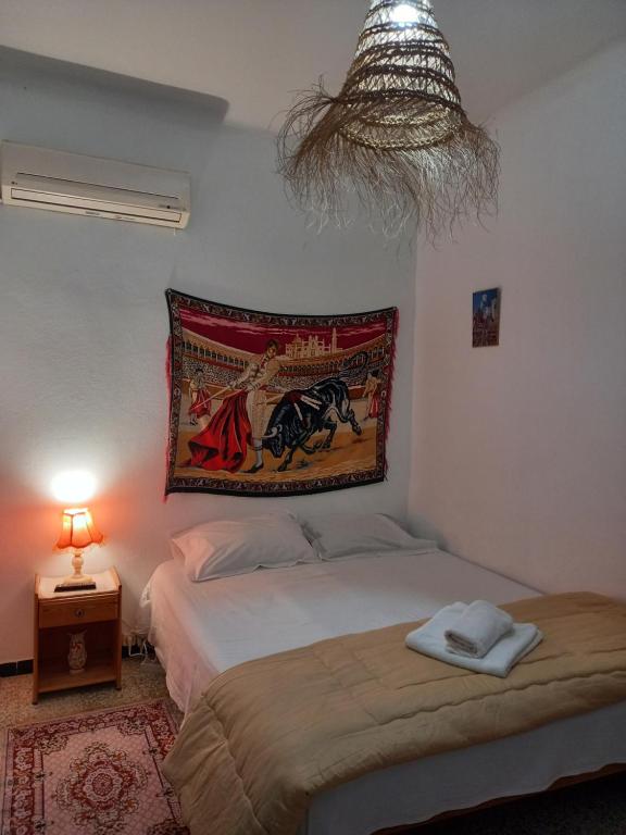 a bedroom with a bed and a tapestry on the wall at Dar Hkaïem in Hammam Sousse