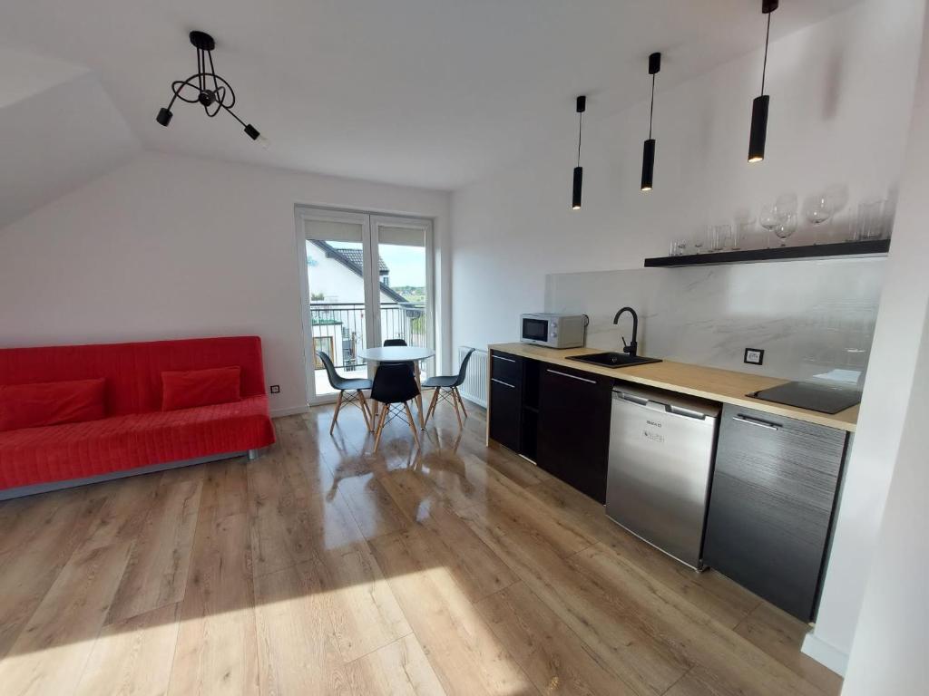 a living room with a red couch and a kitchen at Avilla Apartamenty in Łeba