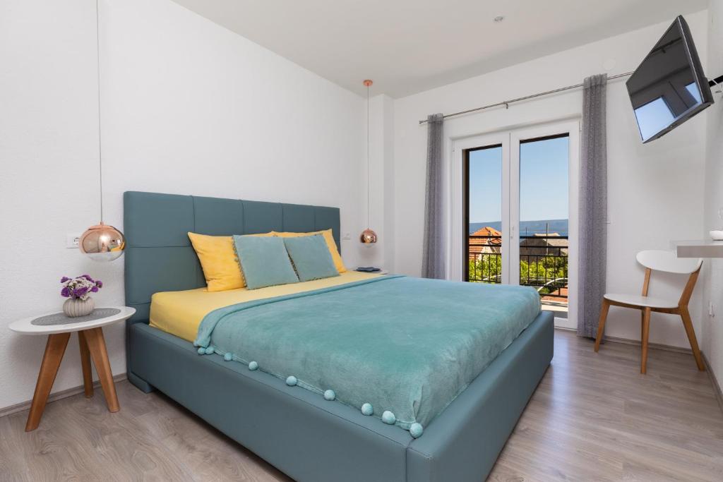 a bedroom with a blue bed and a balcony at Apartments Paloc - Yellow in Bol