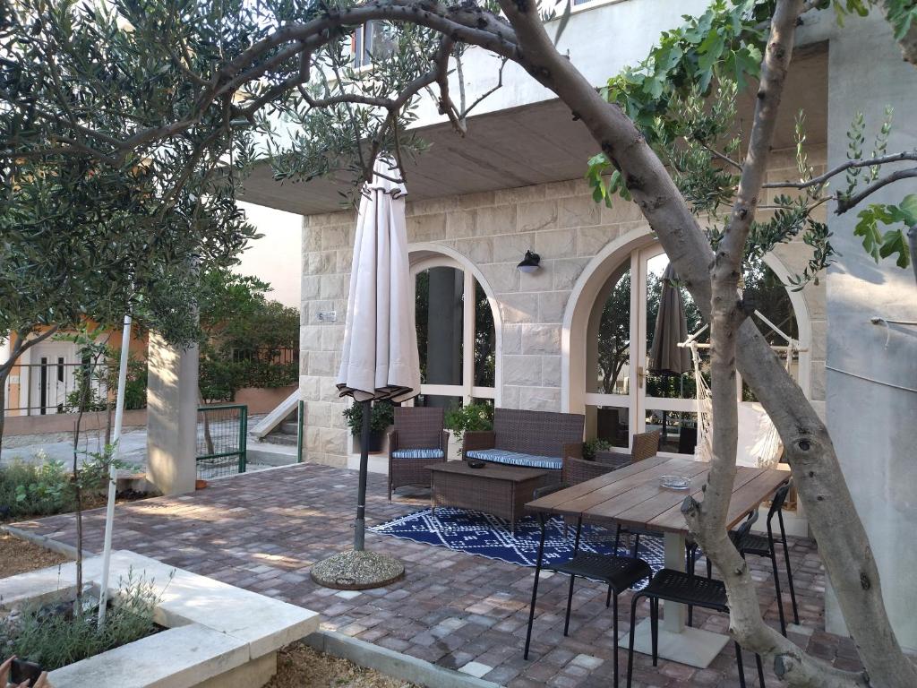 patio ze stołem, krzesłami i drzewem w obiekcie Holiday Home with free parking by the beach w Breli