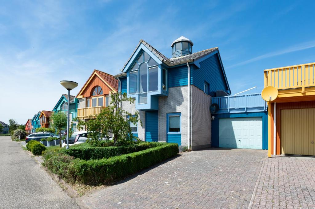 una casa azul con un garaje en una calle en Grimaud 185 - Kustpark Village Scaldia, en Hoofdplaat