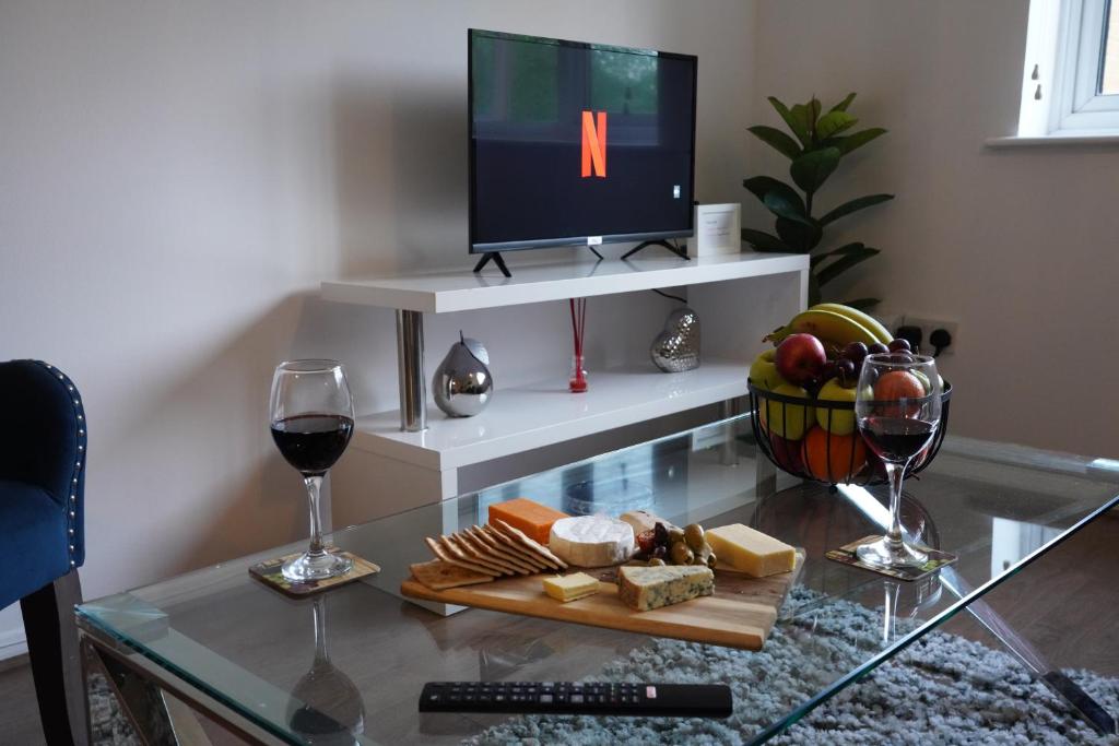 a glass table with a tray of cheese and wine at Jdb West Ham 2-Bedroom with parking in London