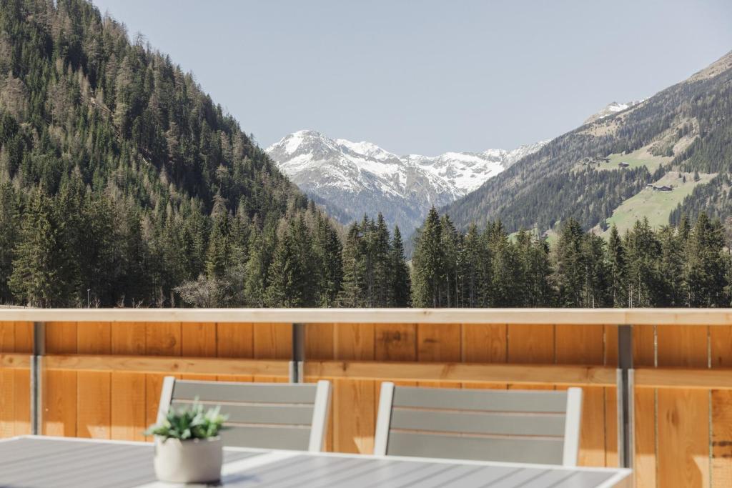 een balkon met 2 stoelen en uitzicht op de bergen bij Chalets Santner in Sankt Jakob in Defereggen