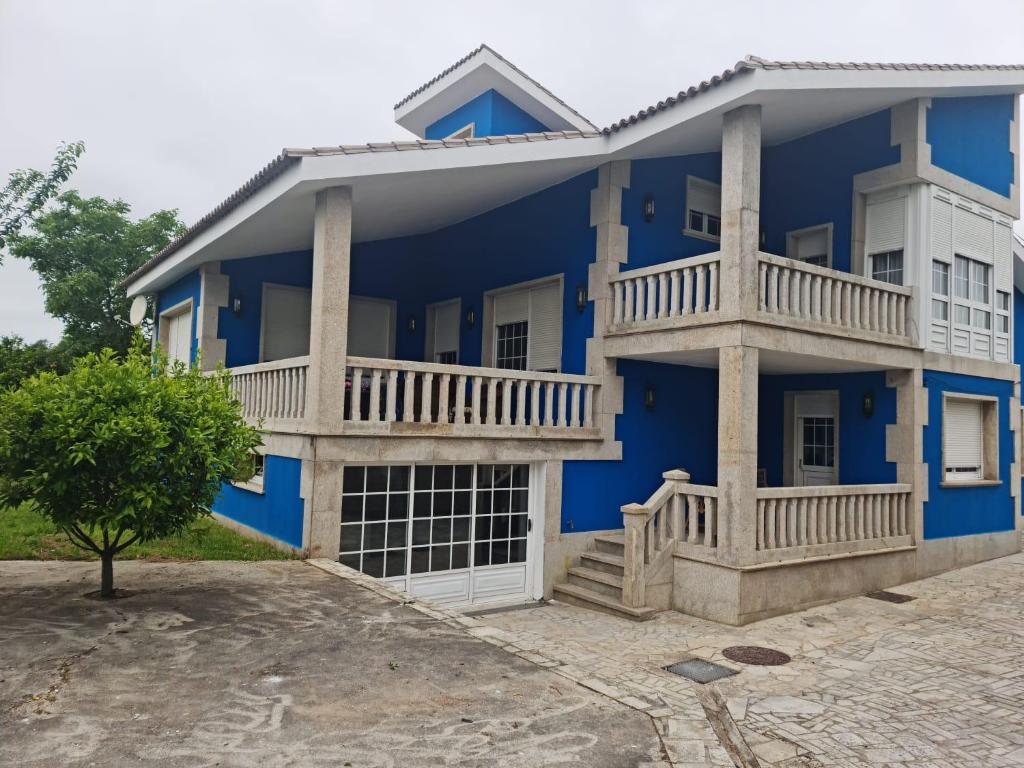 a blue house with a balcony and a tree at CASA GORIS in Villanueva de Arosa