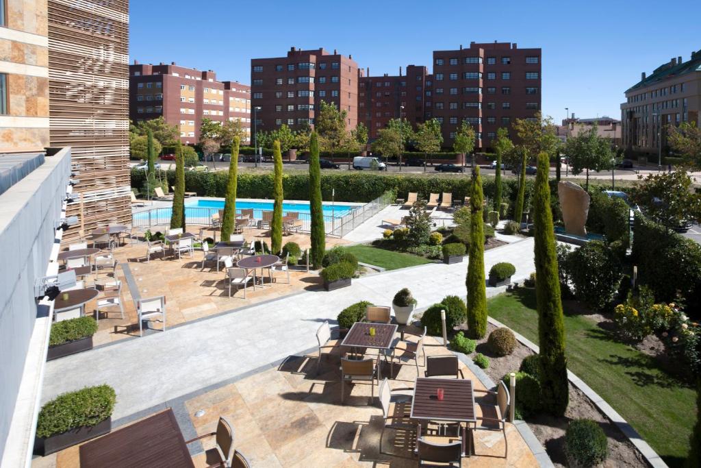 un patio esterno con tavoli, sedie e piscina di Sercotel Valladolid a Valladolid