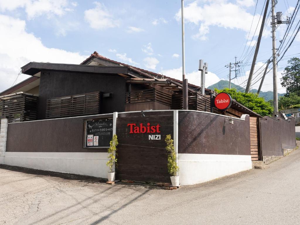 a restaurant with a sign on the side of a building at Tabist Hotel Nizi Fuefuki Misaka in Fuefuki