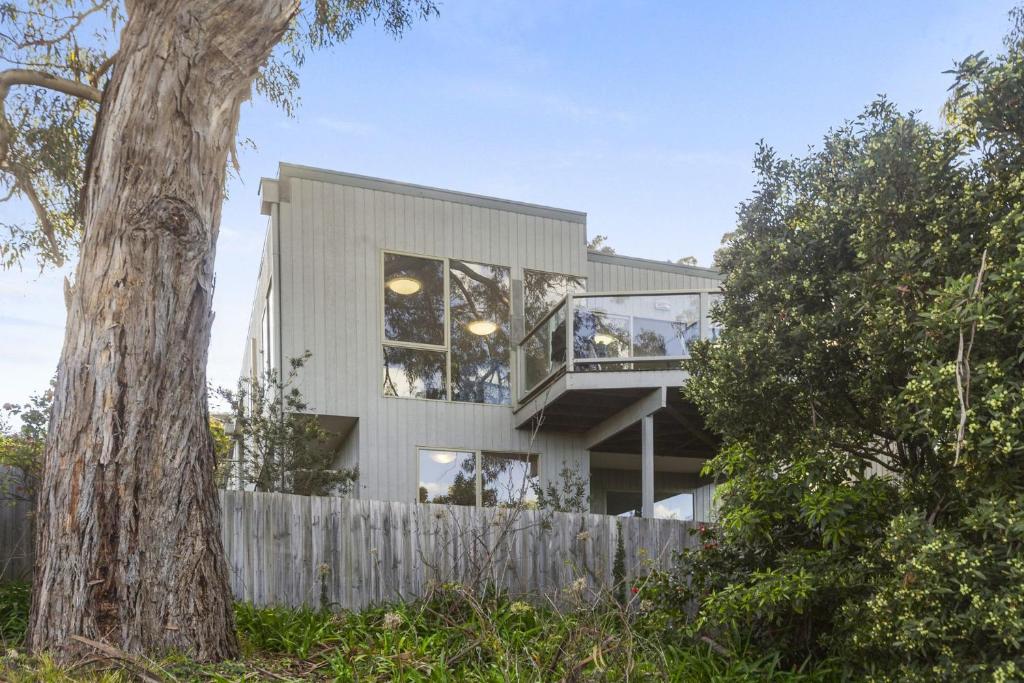 a modern house with a wooden fence and a tree at Beach Bush and Birds in Lorne