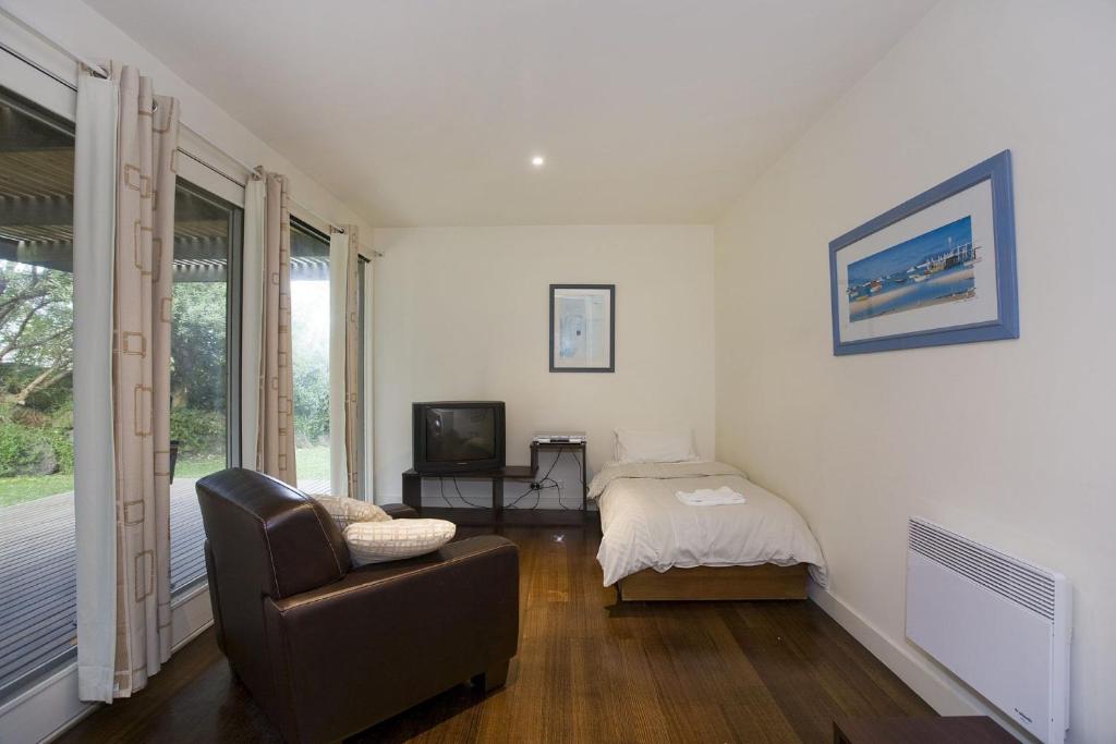 a living room with a couch and a bed and a television at Beachside At Breakers in Lorne