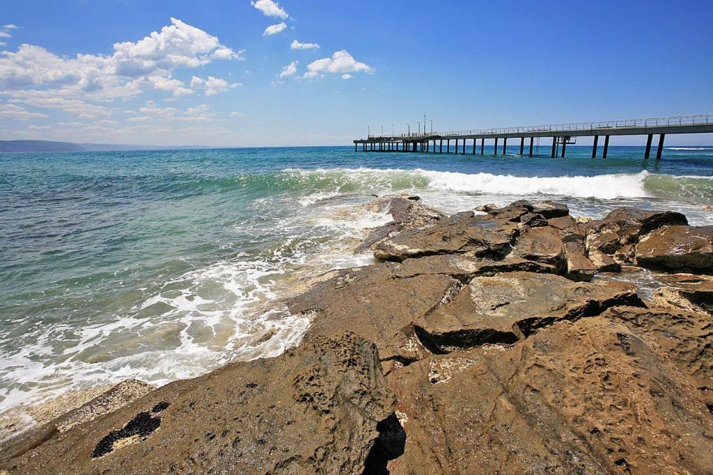a pier in the ocean next to some rocks at Beachside At Breakers in Lorne