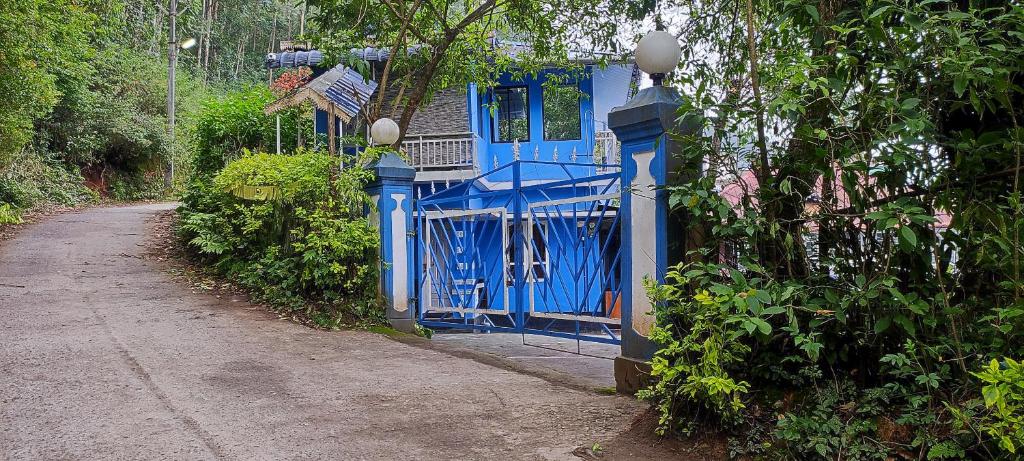 Ein blauer Zaun neben einer unbefestigten Straße in der Unterkunft Munnar happy holidayss in Munnar