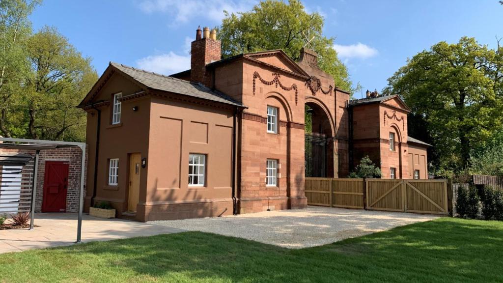 an old brick house with a gate in a yard at Oulton Park Lodge in Little Budworth