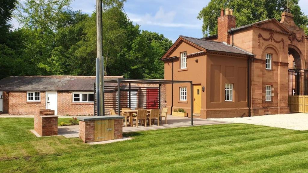a brick building with a table and chairs in a yard at Oulton Park Lodge in Little Budworth