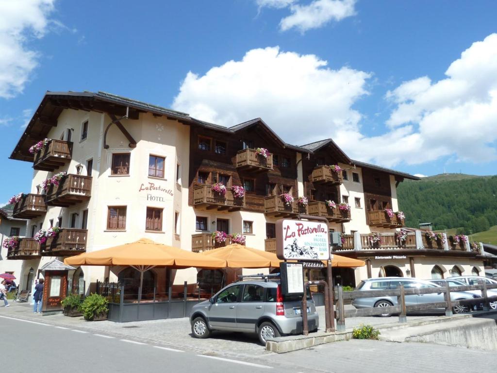 a large building with cars parked in front of it at Hotel La Pastorella in Livigno