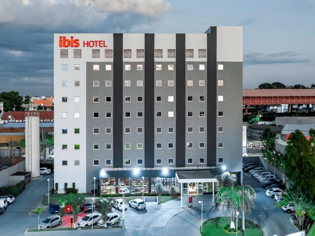 a hotel with a lot of cars parked in a parking lot at ibis Uberaba in Uberaba