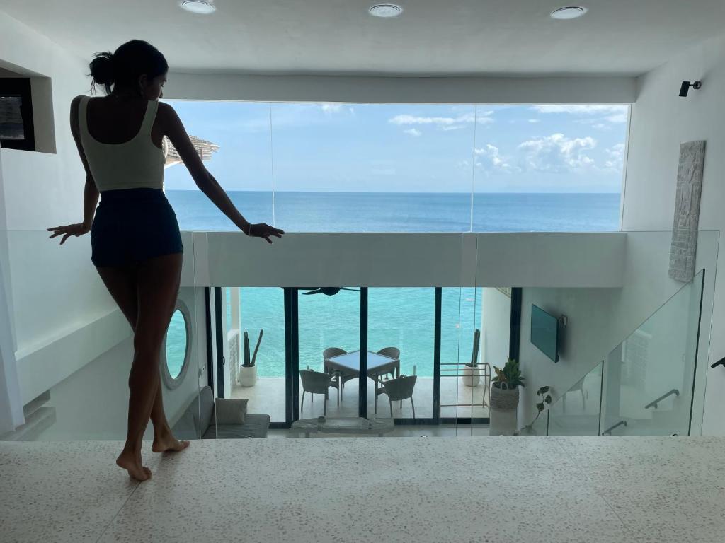 Eine Frau steht in einem Zimmer mit Meerblick in der Unterkunft Infinity Villa - BOUTIQUE BEACHFRONT- 2Bed Luxury Family Suite Bingin Beach in Uluwatu