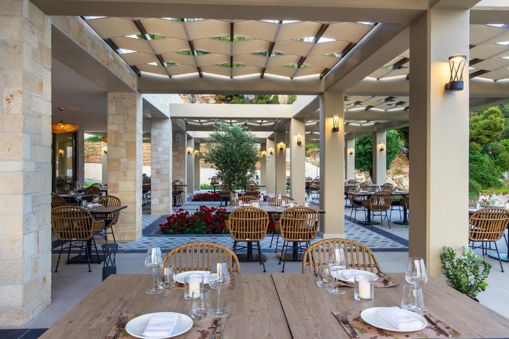 a restaurant with a wooden table and chairs at Ammoa Luxury Hotel & Spa Resort in Nikiti