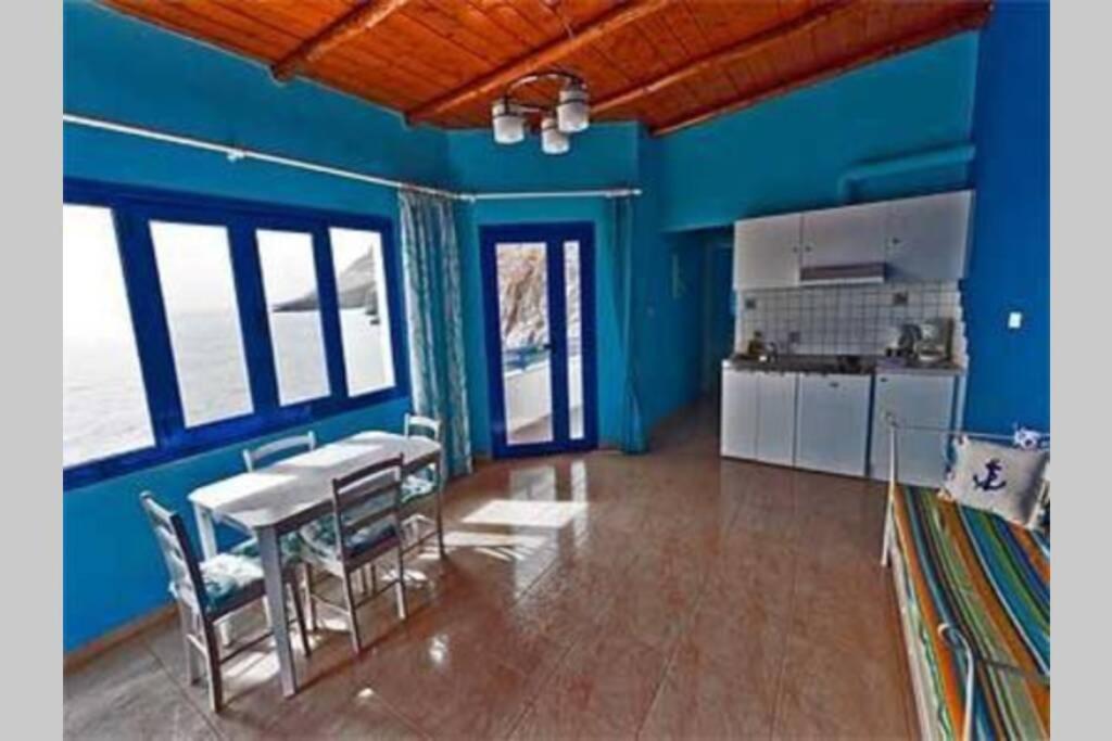 a kitchen with blue walls and a table and chairs at Great sea-view apartment. in Khóra Sfakíon