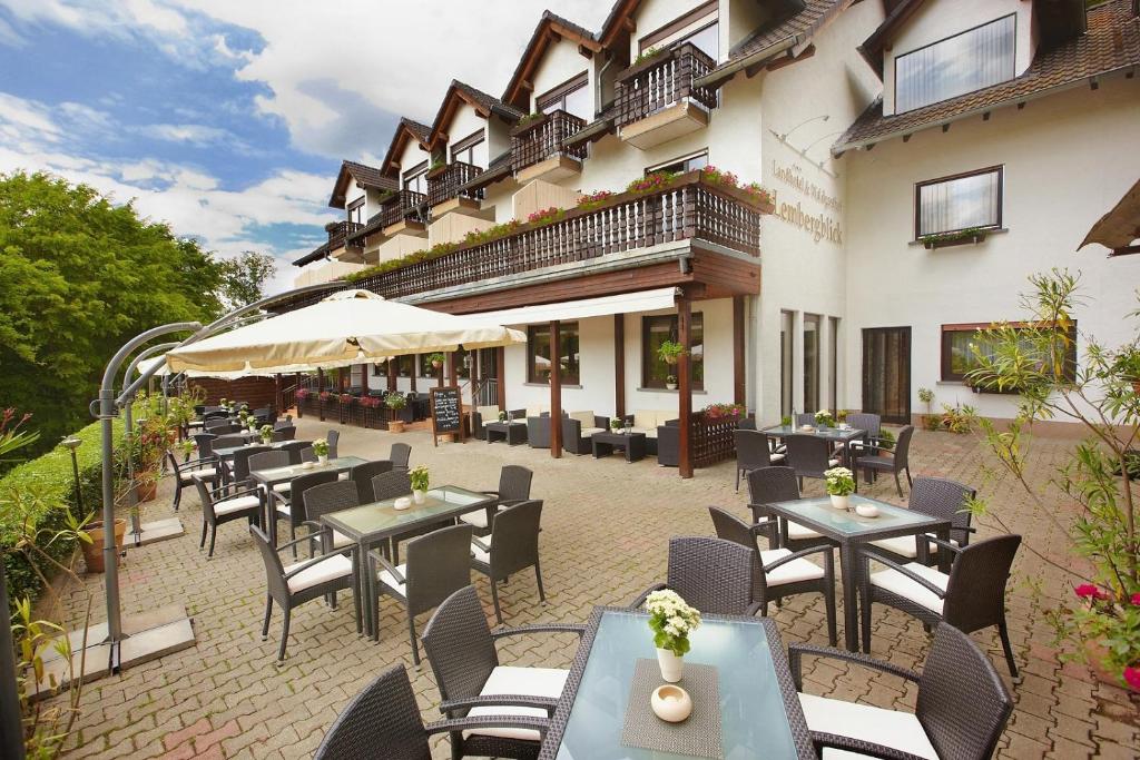 a restaurant with tables, chairs and umbrellas at Landhotel Lembergblick in Feilbingert