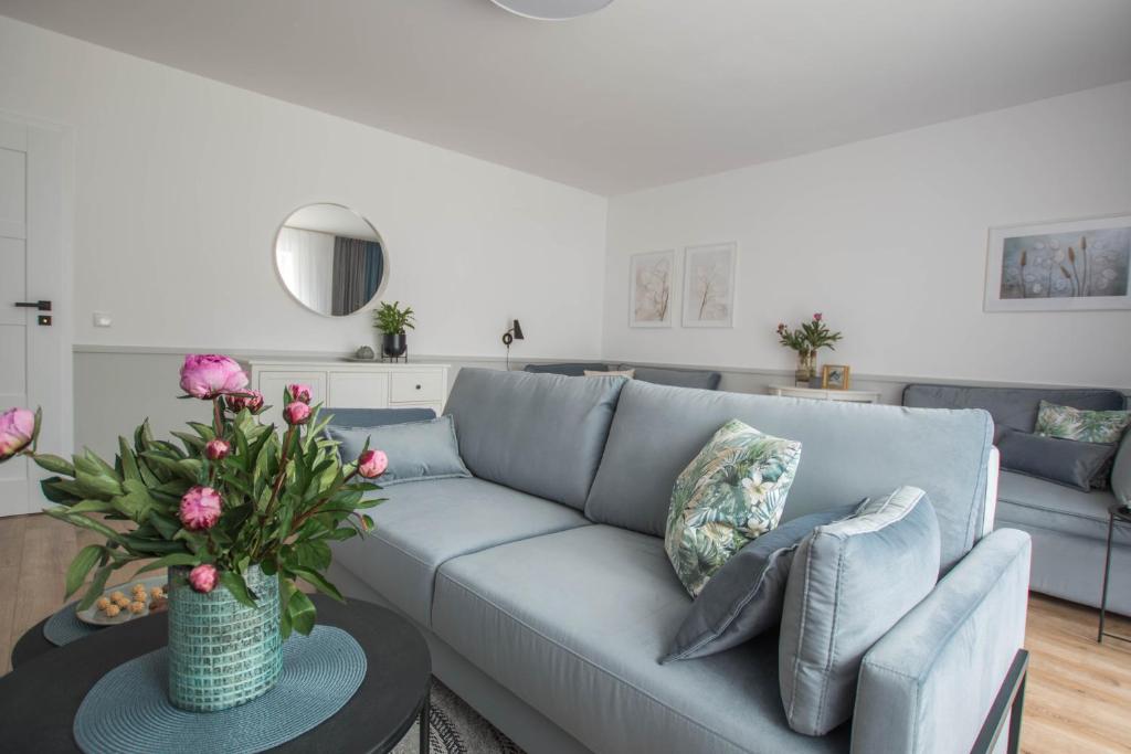 DobraNocka w Leleszkach في باسم: غرفة معيشة مع أريكة زرقاء وطاولة مع زهور