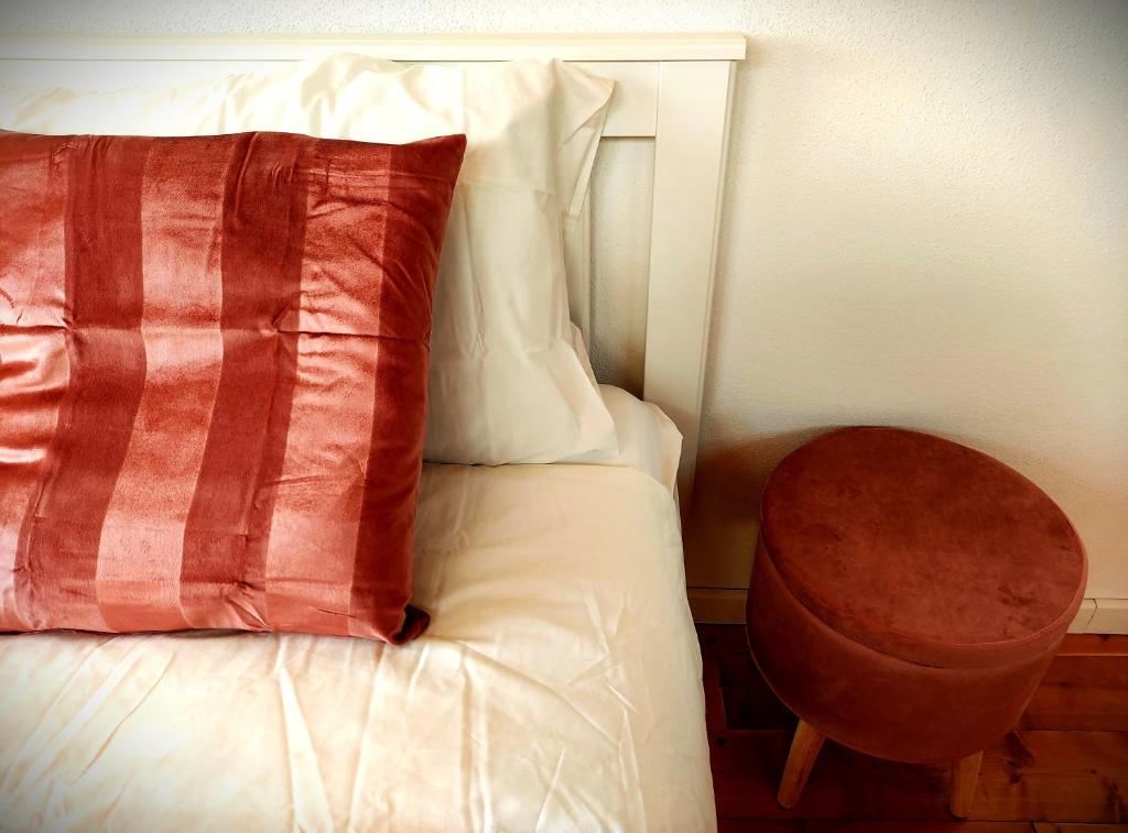 a bed with a red pillow and a table at Our Happy Place - casa vacanze per il viaggiatore Slow in Mandello del Lario