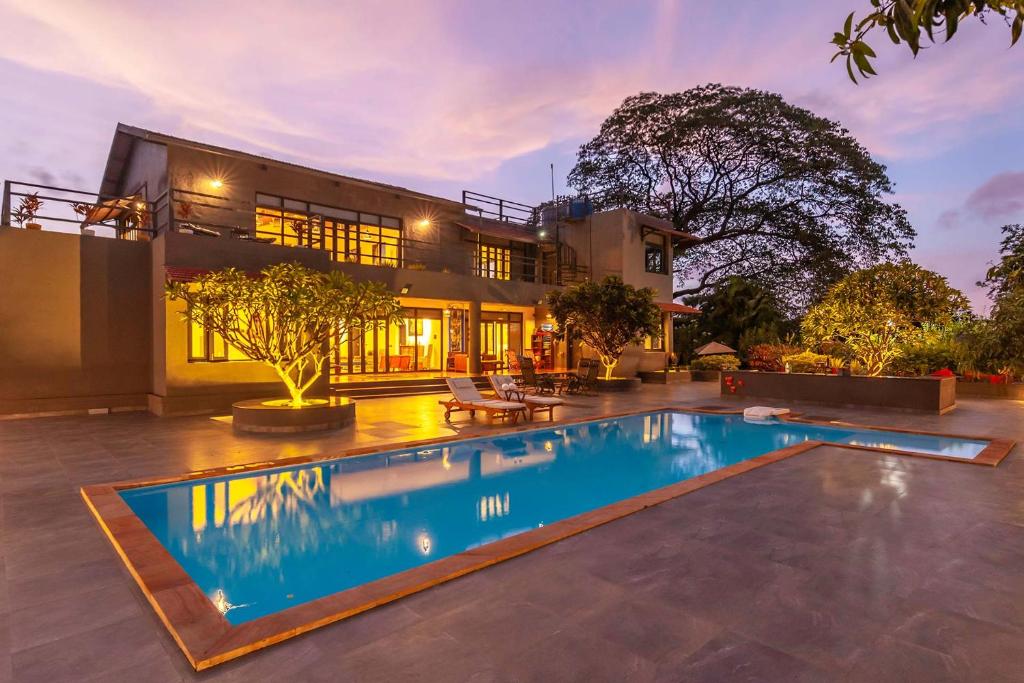 uma casa com uma piscina em frente em StayVista at El Parque em Alibaug
