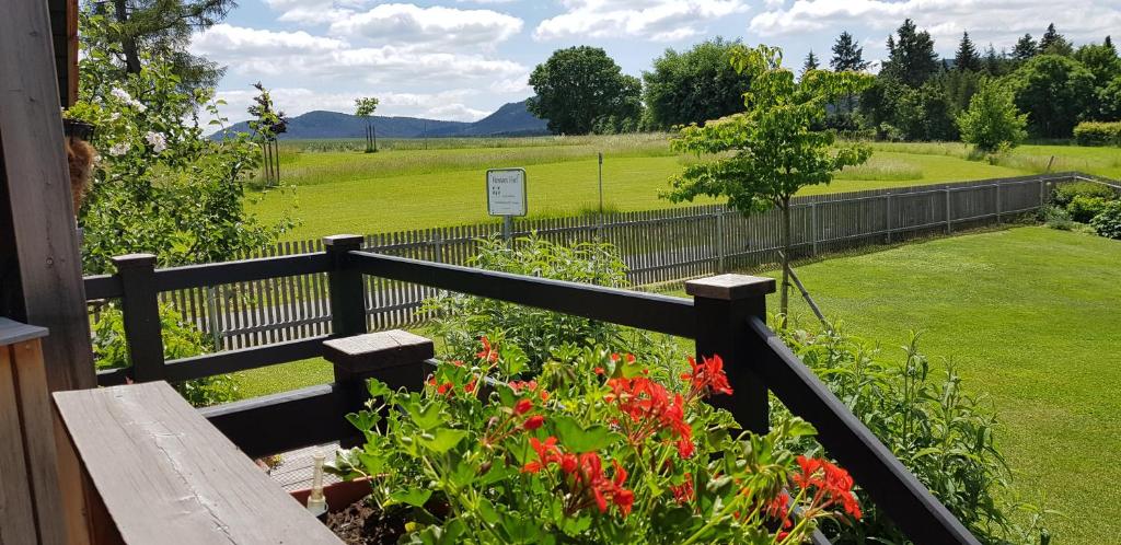 un jardin avec des fleurs rouges et une clôture dans l'établissement Hossies Hof - Luxus Ferienhaus Scheune, à Bertsdorf