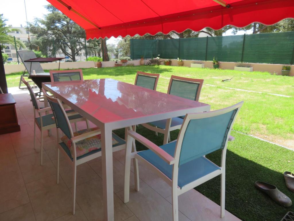 une table et des chaises sous un parapluie rouge dans l'établissement Superbe Rez de Jardin dans résidence au calme, à Nice