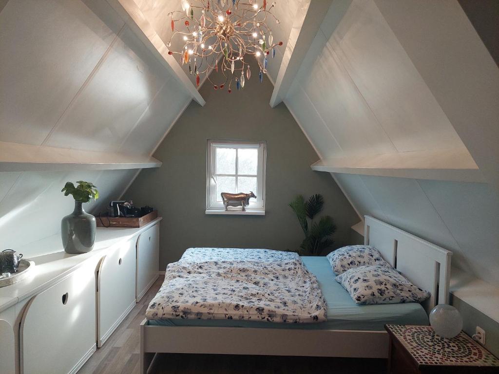 1 dormitorio con cama y lámpara de araña en Chez Bob, en Bovenkarspel