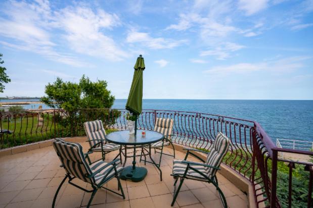 une terrasse avec une table, des chaises et un parasol dans l'établissement Vila Rasarit de Soare, à Costinesti