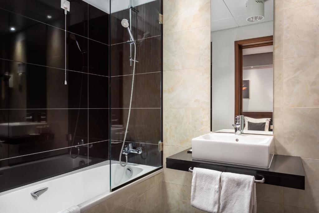 A contemporary bathroom with a sink and a bathtub fitted with a shower.