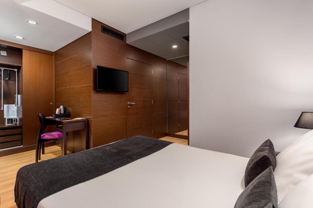 A double room with a compact desk, tea station and wood-paneled entry wall.