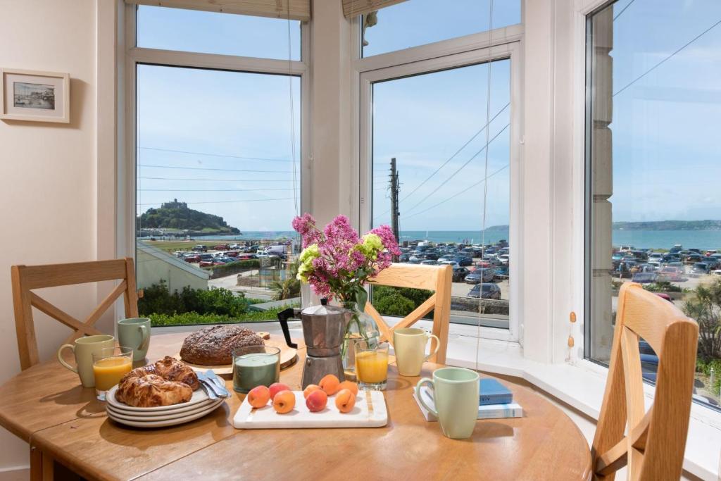 a table with breakfast food and a view of a city at Cormorant Views, Marazion in Marazion