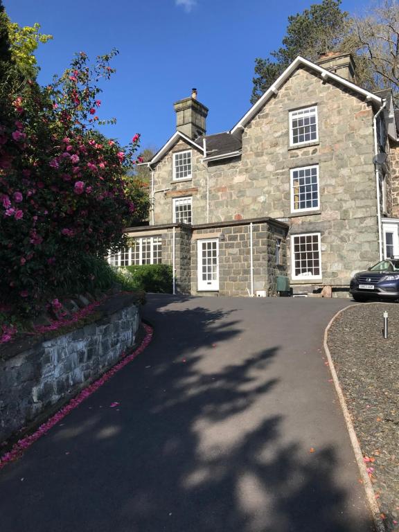 une grande maison en pierre avec une voiture garée dans l'allée. dans l'établissement Bryn Mair, à Dolgellau