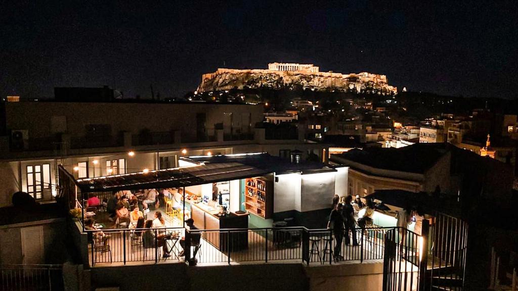 um grupo de pessoas de pé em uma varanda à noite em Mosaikon em Atenas