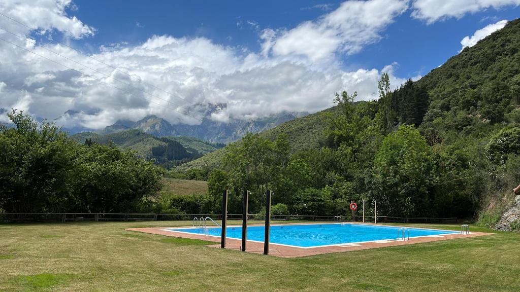 a swimming pool in a field with mountains in the background at Albergue La Cabaña in Turieno