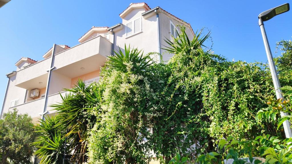 a white building with trees in front of it at Apartments Mazuran in Hvar