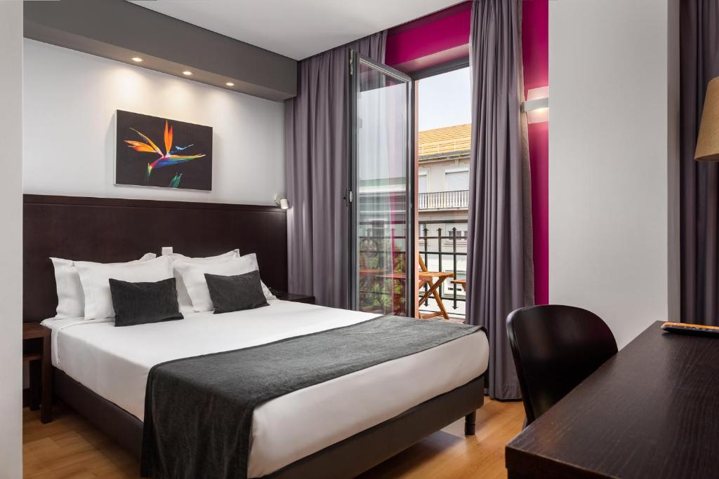 A double room with a small balcony, desk and city-facing window.