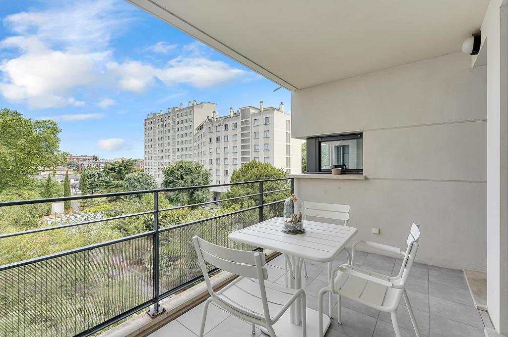 une table blanche et des chaises sur un balcon avec vue dans l'établissement Le Prieuré, à Toulouse
