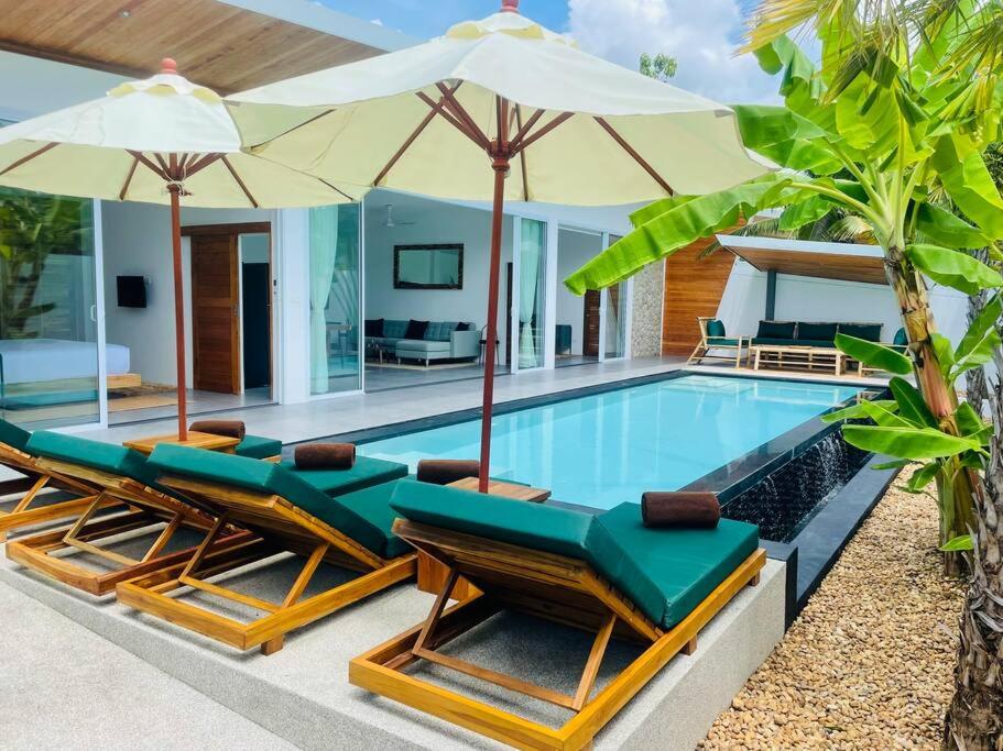 a swimming pool with lounge chairs and umbrellas at Villa Kurma, Modern & Tropical, 2BR, Near Fisherman Village in Bophut 