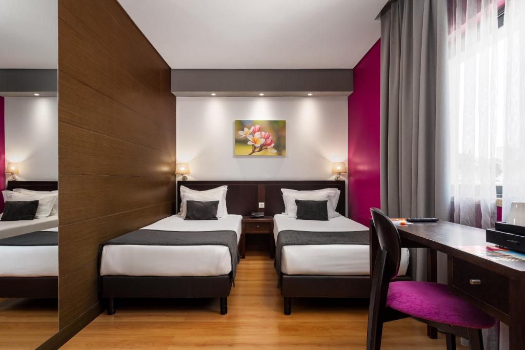 A twin room with a full desk, office chair and bright curtained window.