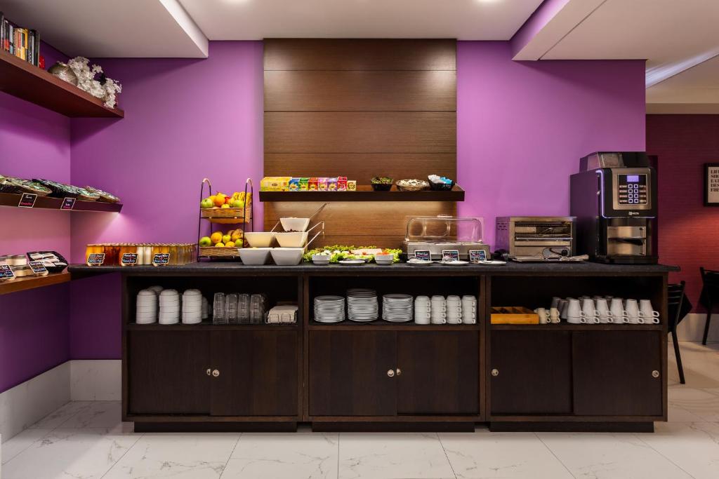 A colourful breakfast counter with fruit, cereals, drinks and coffee equipment.