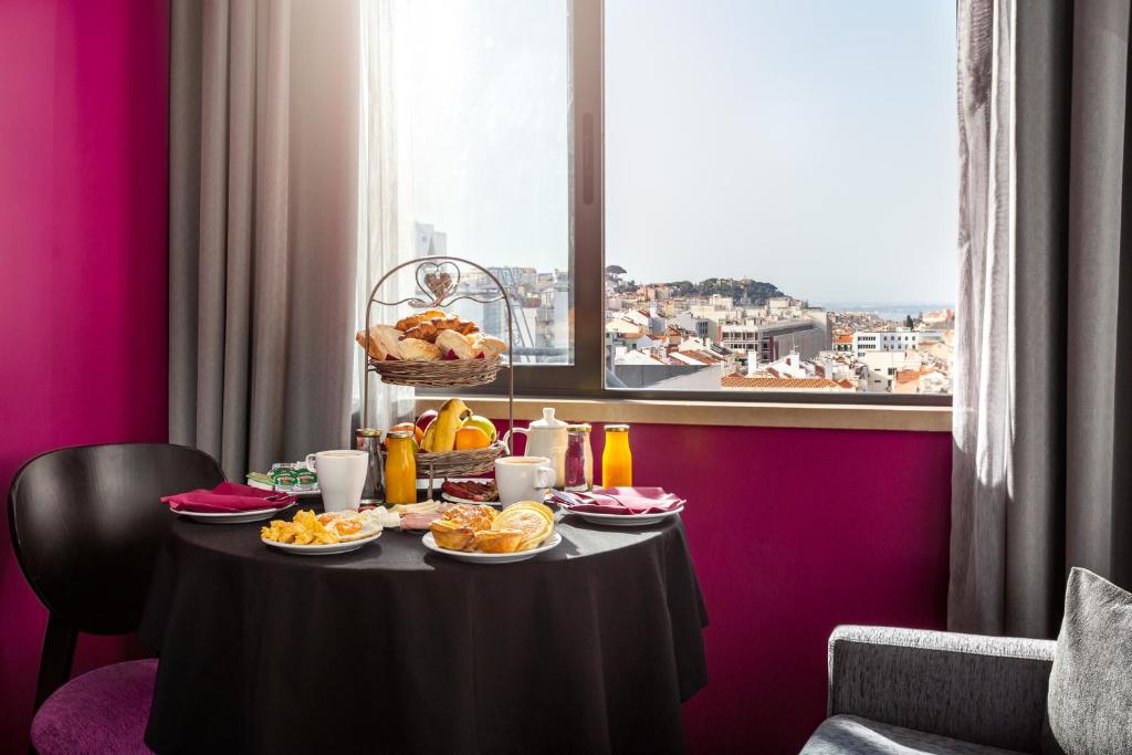 A breakfast table set beside a large window overlooking Lisbon rooftops.